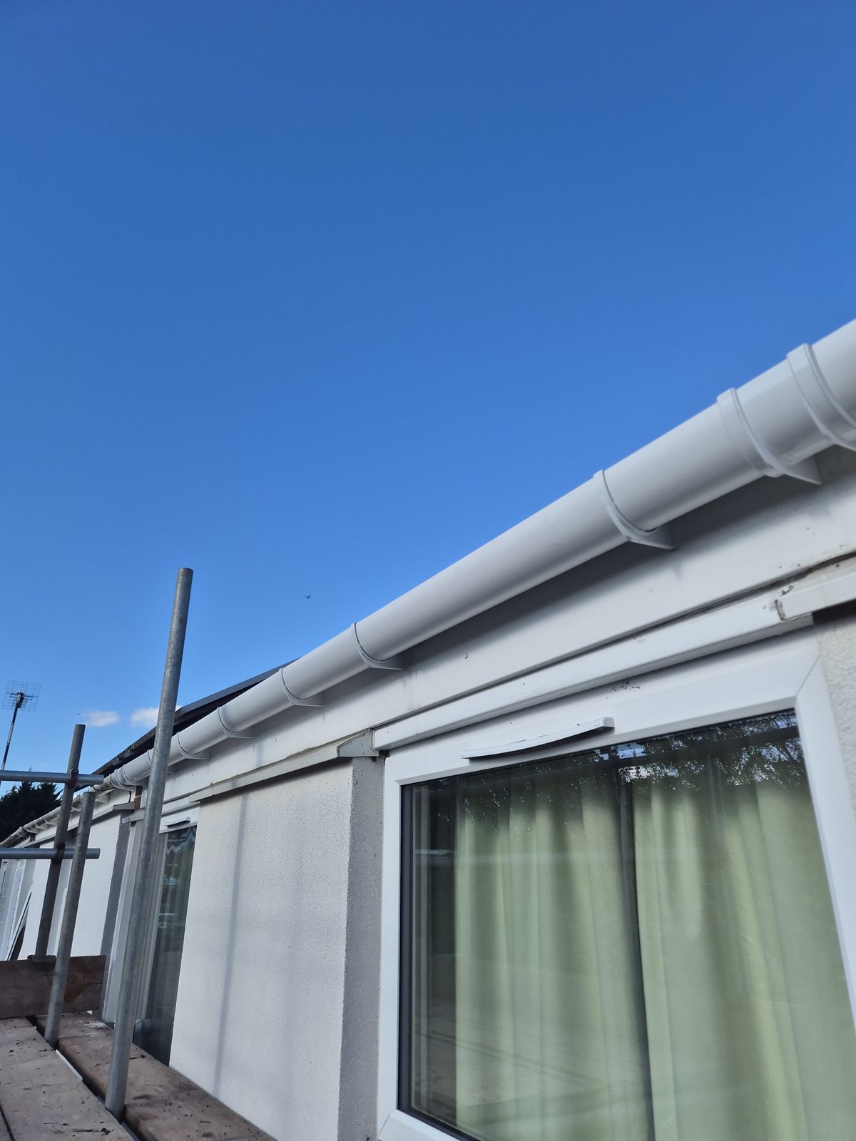 New white UPVC guttering installed along a fascia and brick wall