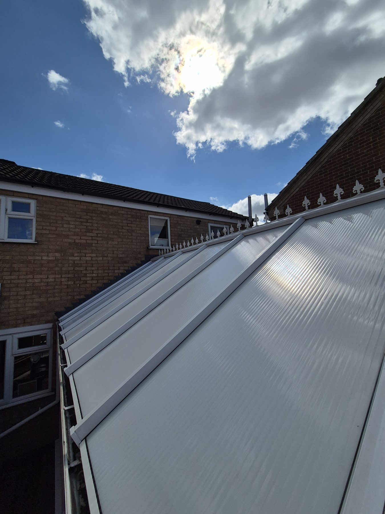 Close-up showing damaged roof tile overhang above newly fitted black UPVC guttering